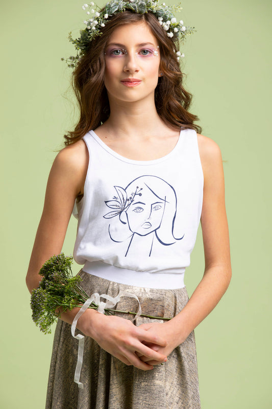 Girl wears a flower crown and gracefully holds a bustle of greenery wearing the Ofelia Tank Top