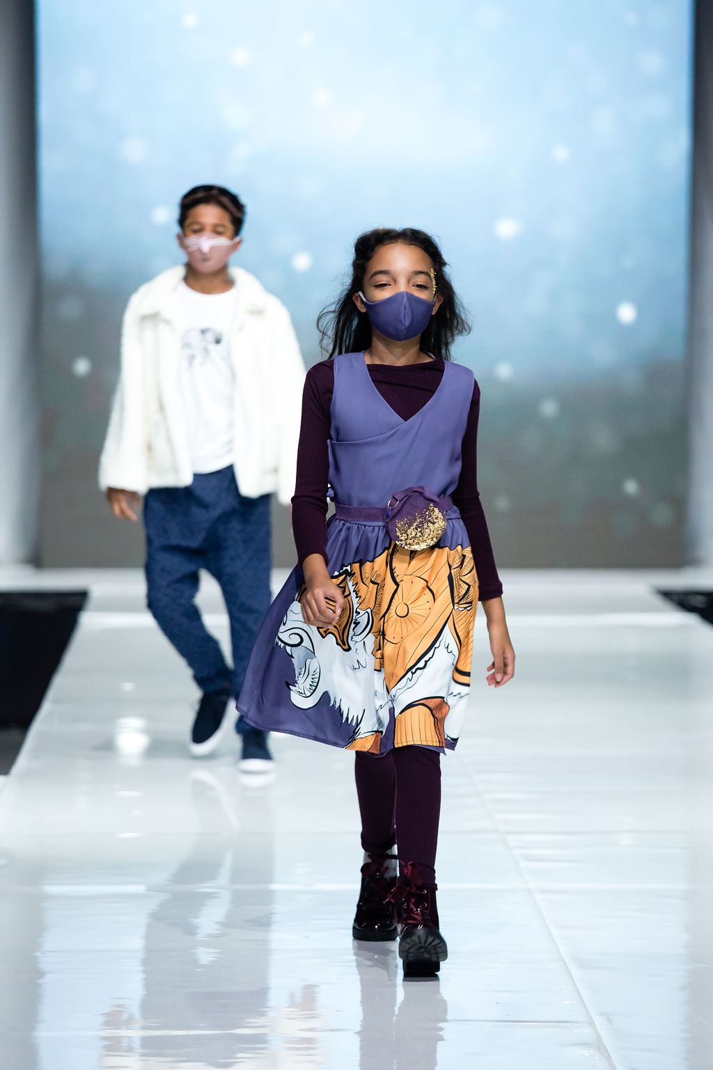 Girl walks the runway with in her purple knit leggings and tunic under her lorek dress