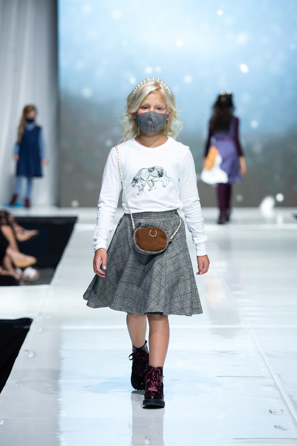 Young girl confidently walks the runway in her lorek shirt, scholars skirt, and matching satchel 