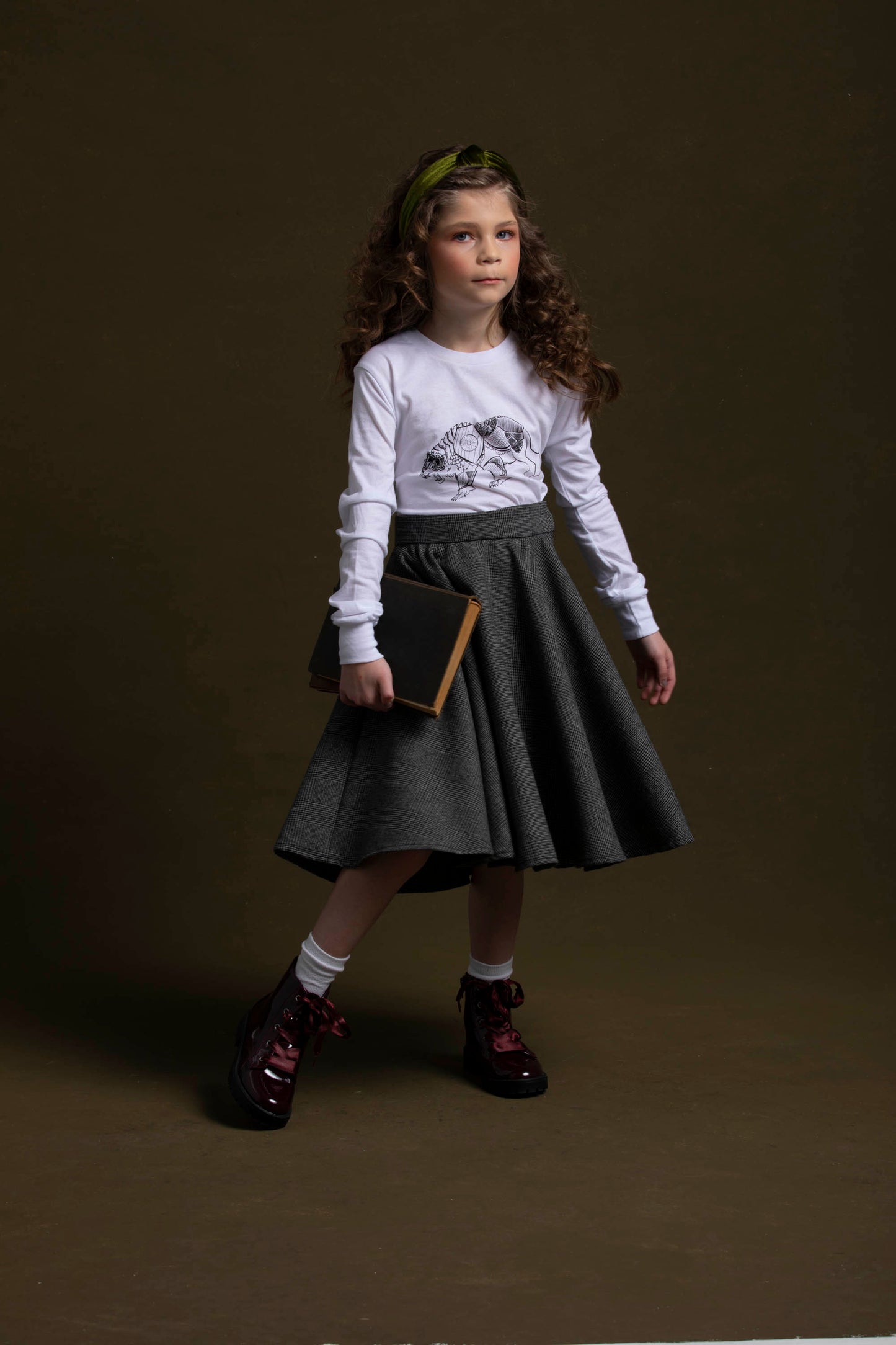 Beautiful young girl flares her scholars skirt paired with her lorek T-shirt while holding a book