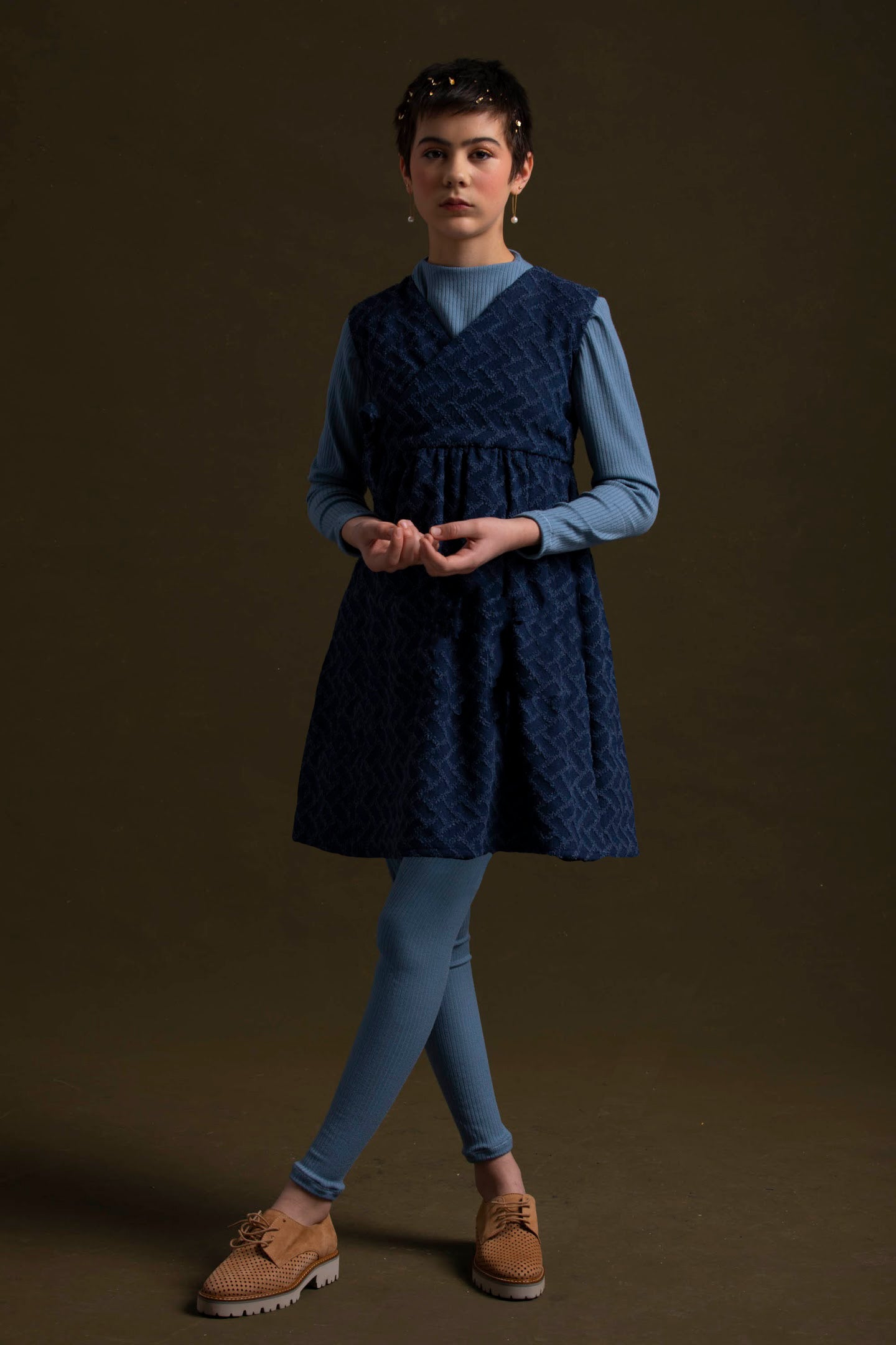 Young lady with pixie cut wears her subtle knife dress paired with blue rib knit tunic and leggings