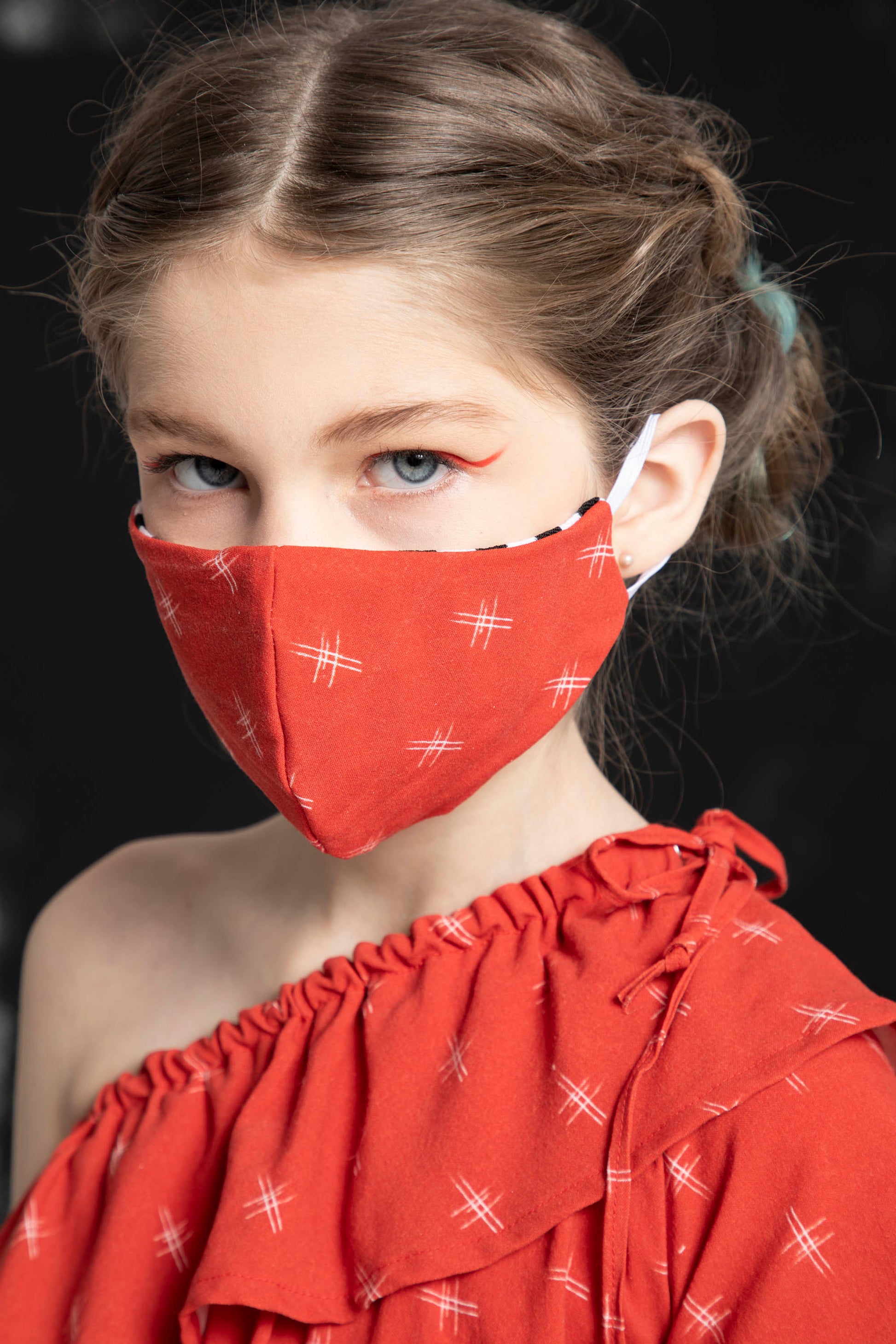 Close up of a girls face wearing the matching face mask to the red print on the Oracle dress