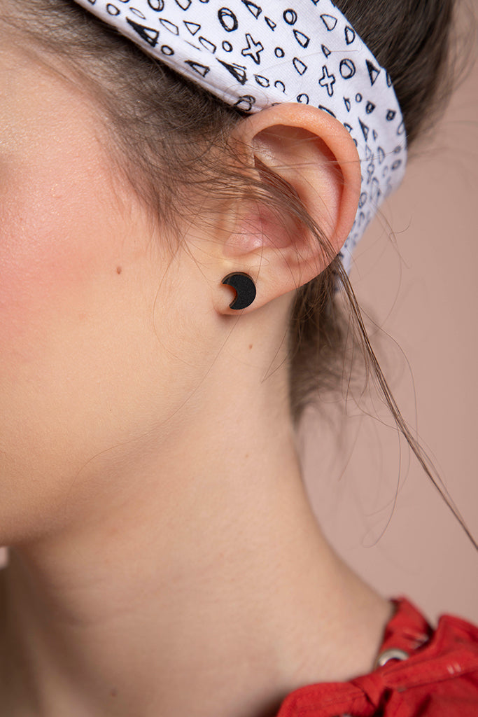A close shot of an ear shows gives a closer look at the black crescent moon shaped earrings