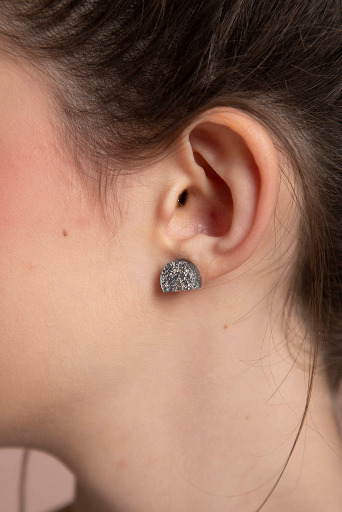 Close up of a glittery silver arch earring on the left ear.