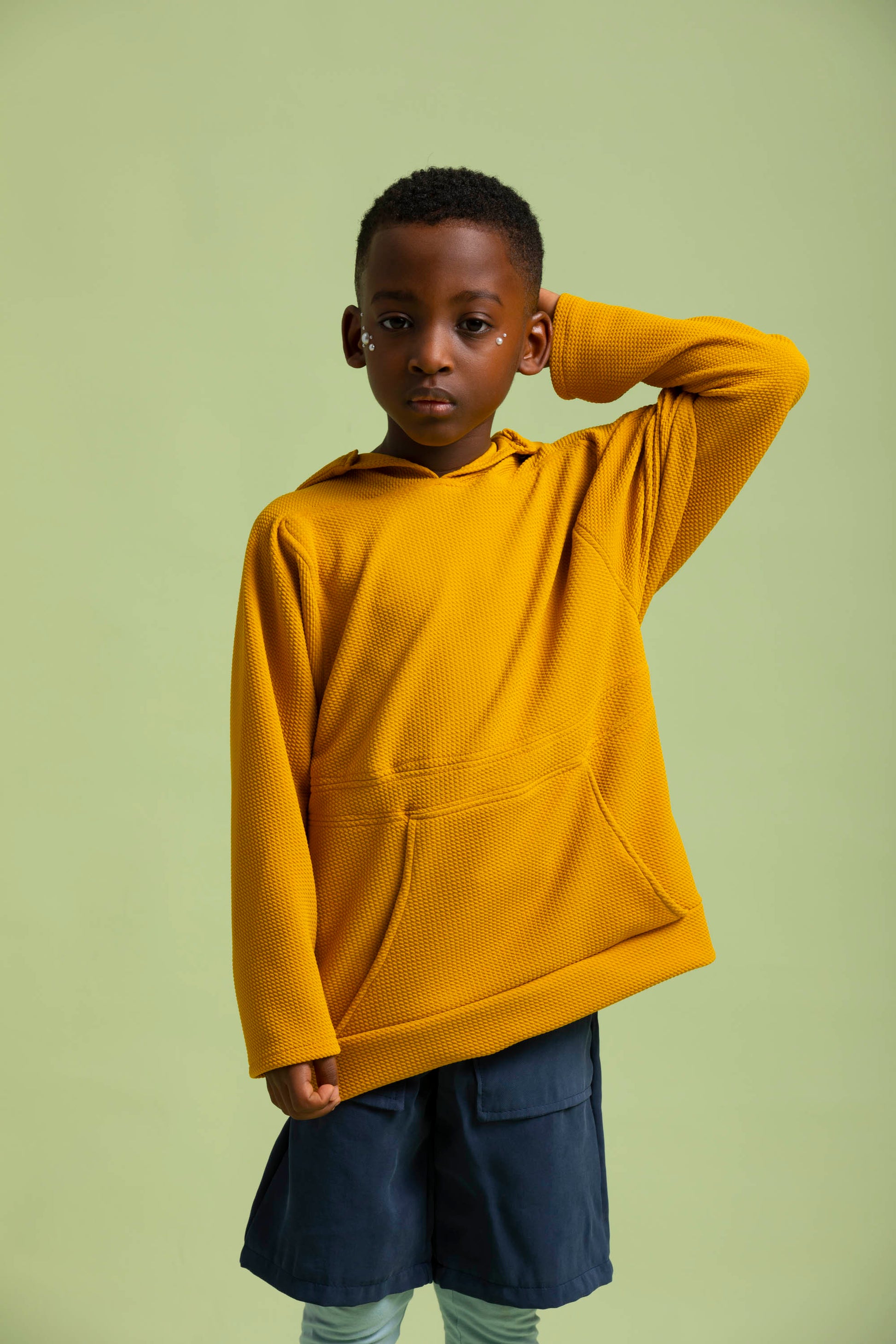 A closer shot of a boy wearing the yellow pan hoodie gives a closer look at his Fauno shorts