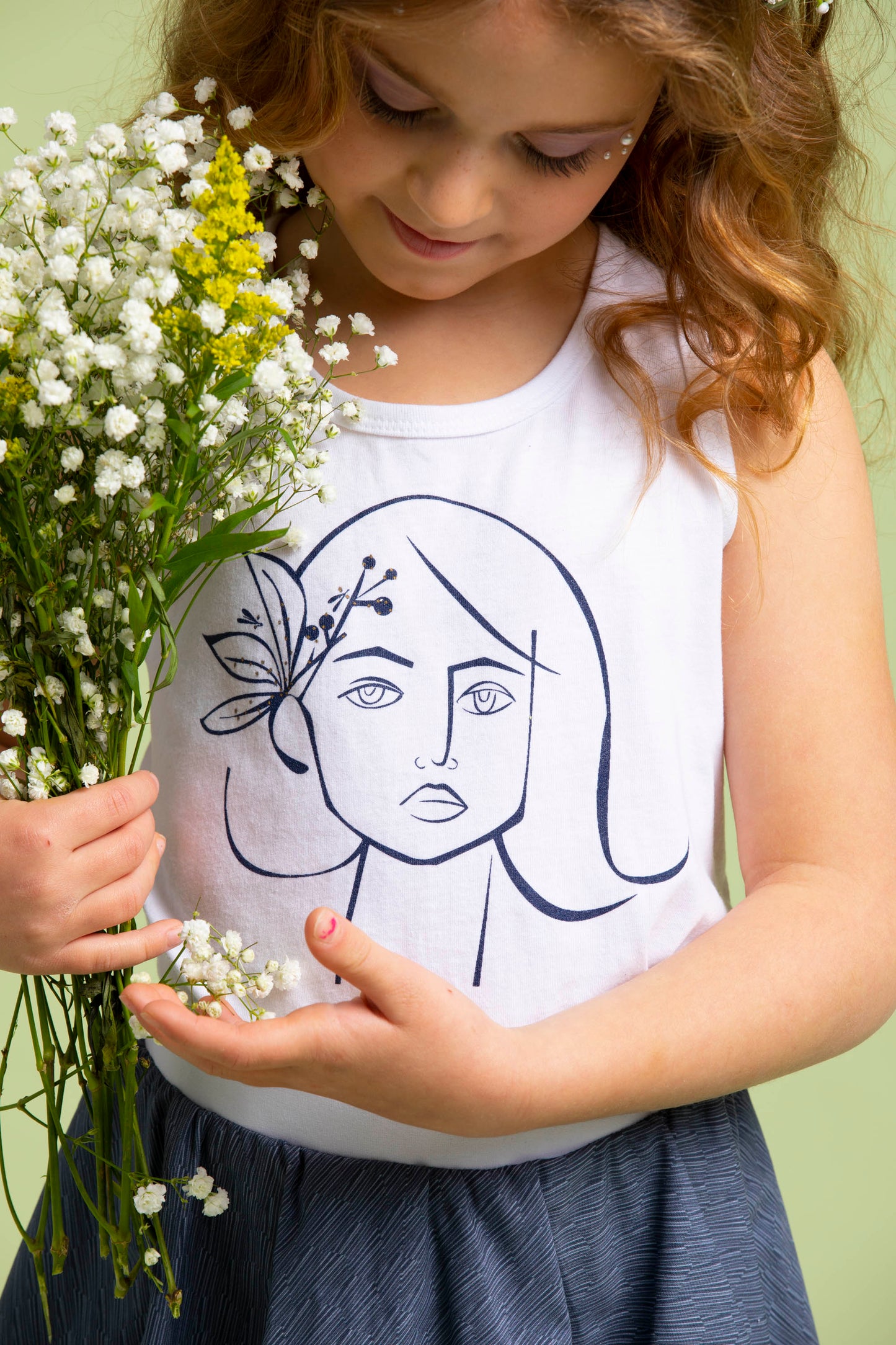 Close up of the Ofelia print on the Ofelia Top that the young girl is wearing while holding flowers.