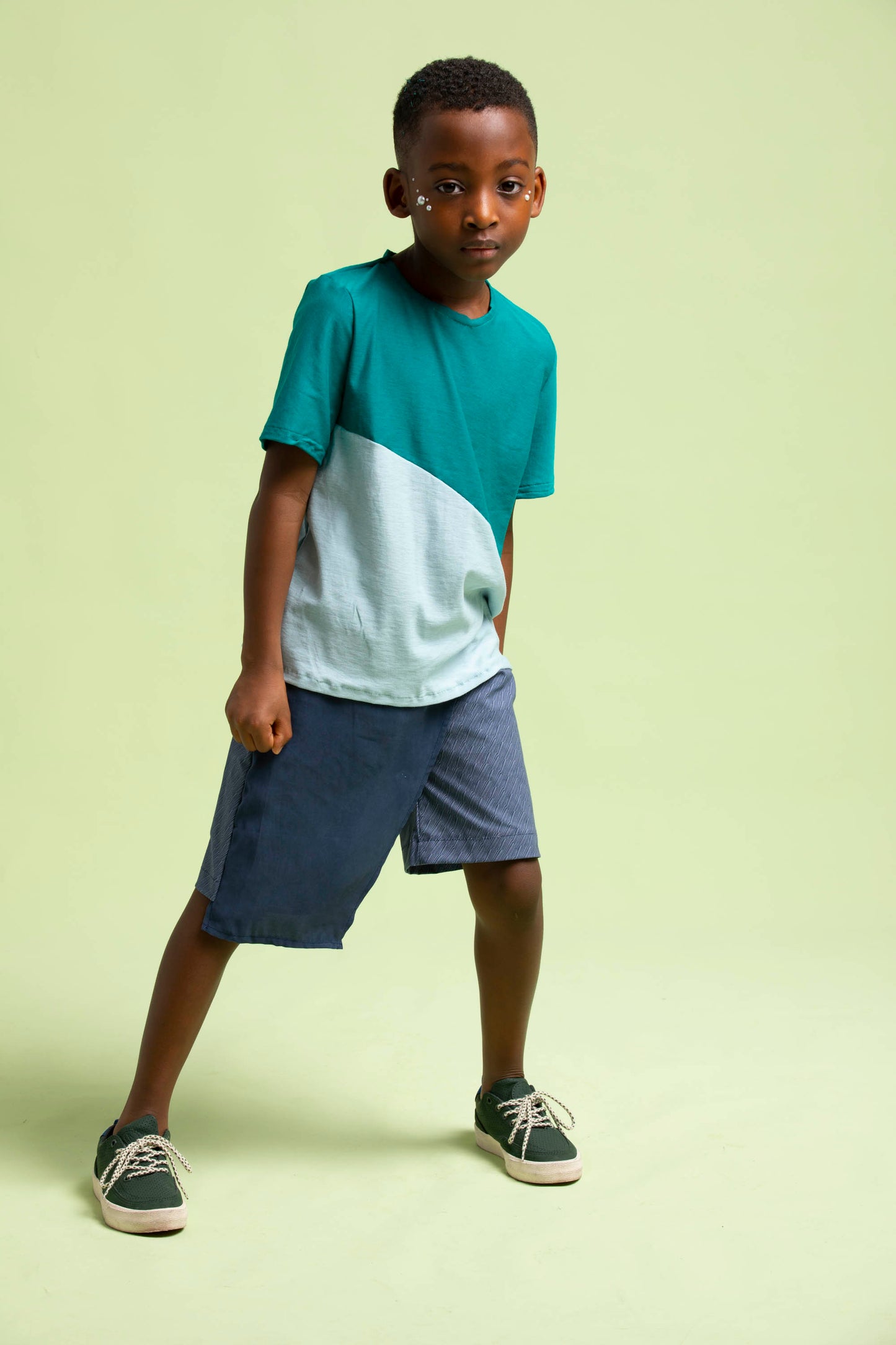 Young man leans legs apart and to the side to show off the asymmetrical wrap on his maze shorts