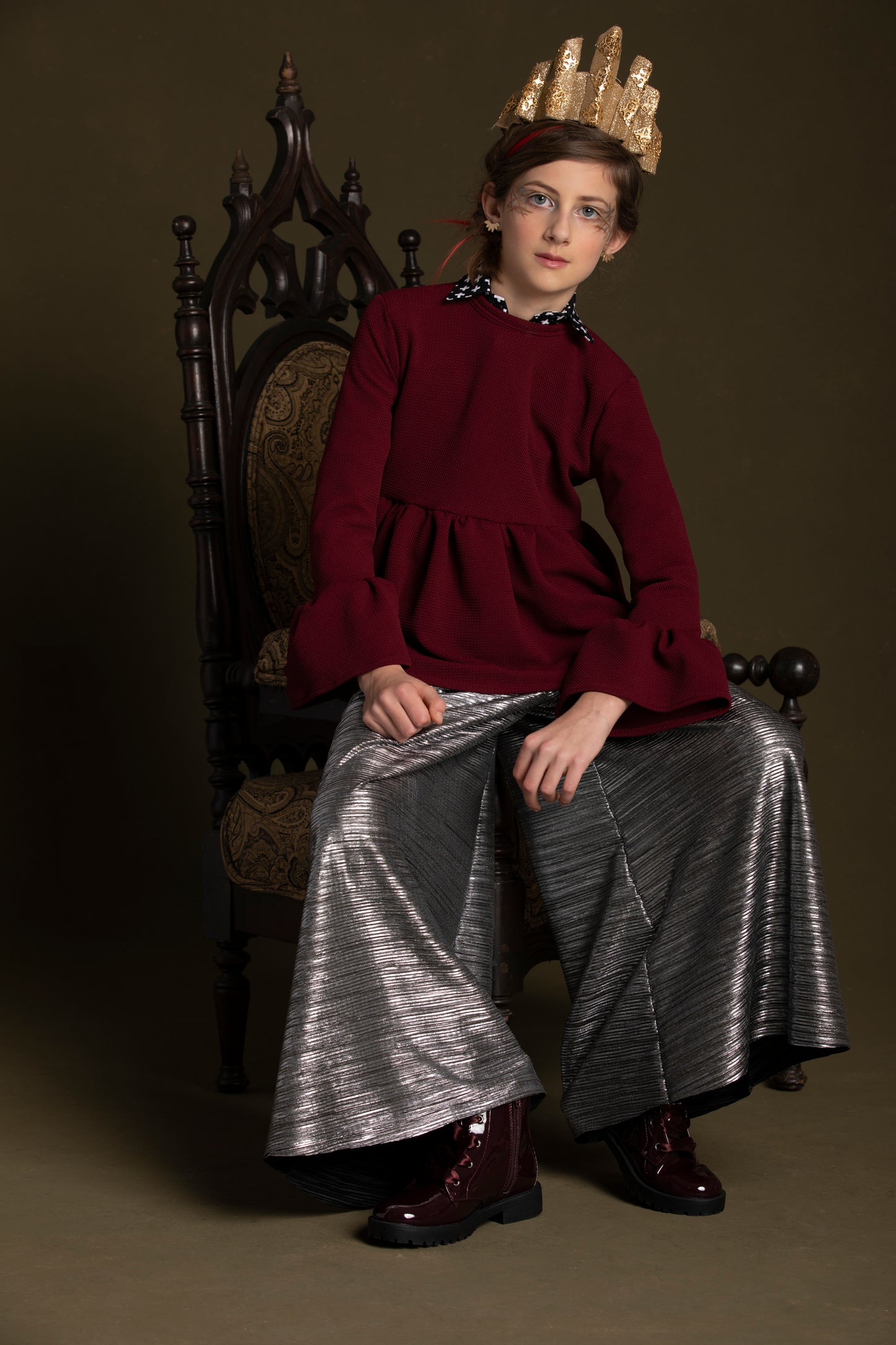Sitting on her throne this queen wears her burgundy knit tip over her snap down with metallic pants