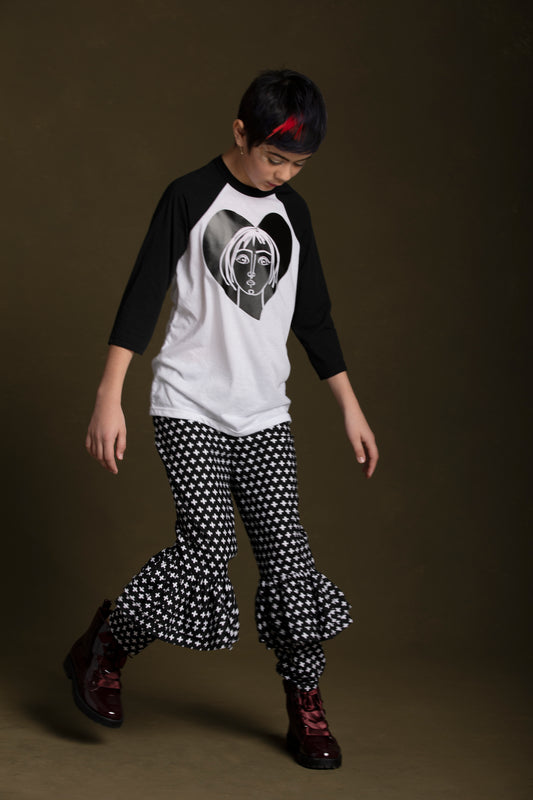Young lady wears her Joan T-Shirt paired with her plus print ruffle pants in an exaggerate pose